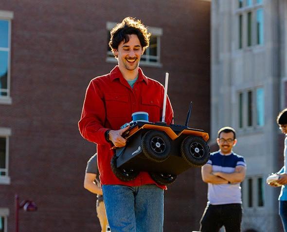 Alumnus 和 graduate student Ori Miller, carrying a robot that the ARISE lab uses in its research