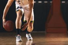 image of a basketball player from the neck down crouched 和 dribbling.